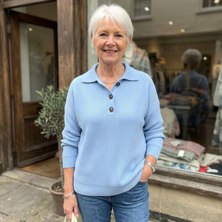 Constance polo-collar button jumper in Sky Blue, worn in front of a boutique