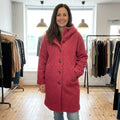 Corinne cosy hooded button coat in Pink, worn in a boutique