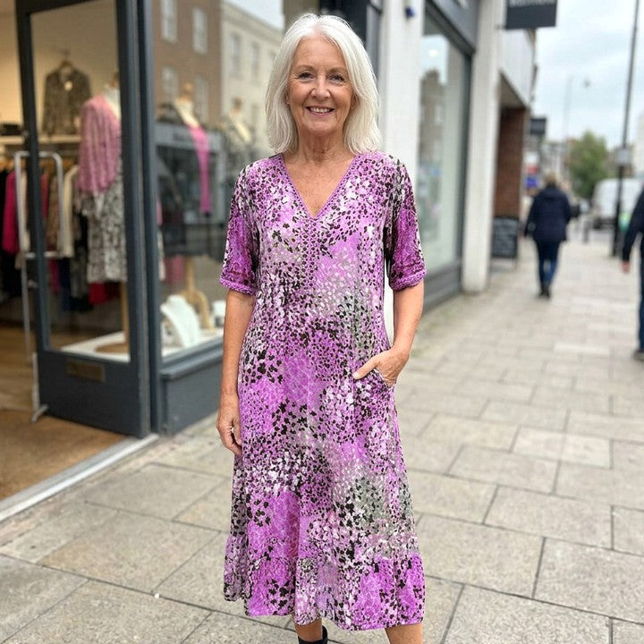 Iris flowing midi dress in Purple, worn in front of a boutique