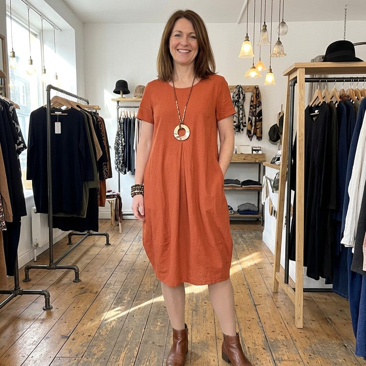 Kwani flowing dress in Orange, worn in a boutique