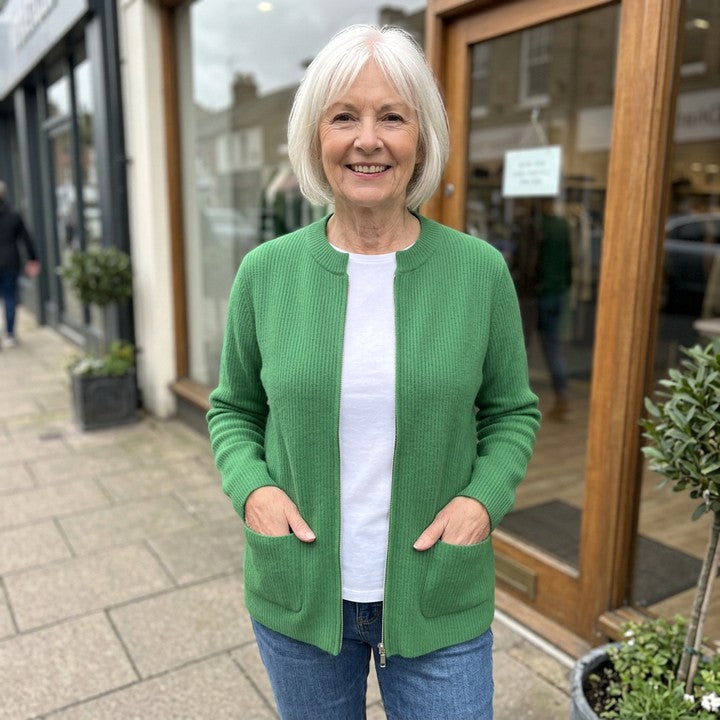 Margot zip-up cardigan in Green, worn in front of a boutique