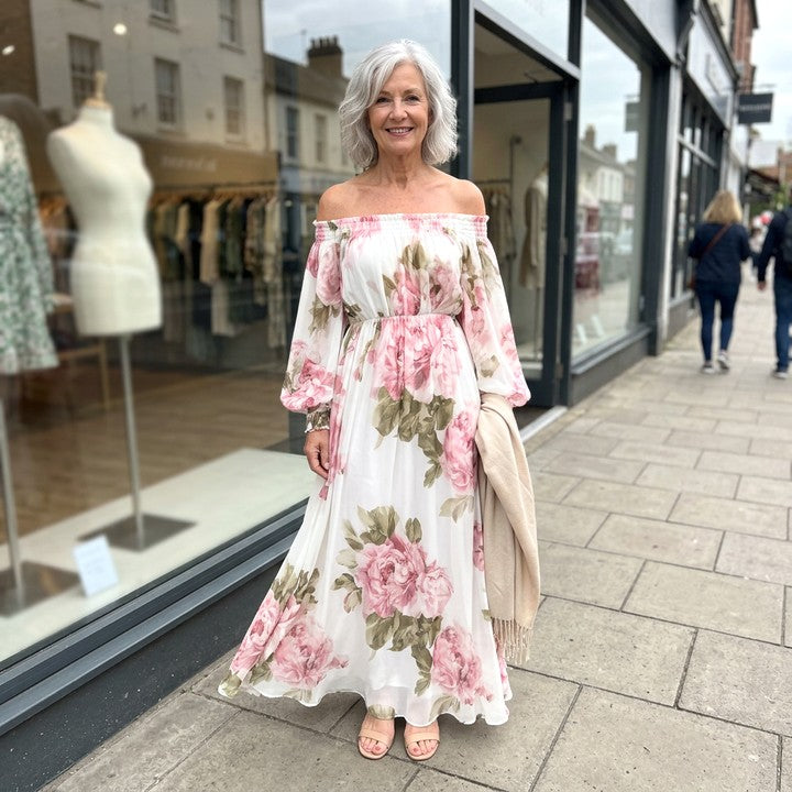 Rosalie floral off-shoulder maxi dress in White, worn in front of a boutique